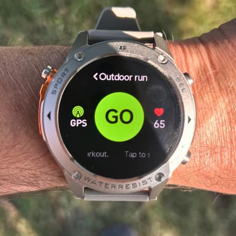 Smartwatch on a wrist with 'Outdoor run' app displayed, showing GPS and heart rate information.